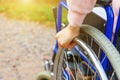 Hand handicap woman in wheelchair wheel on road in hospital park waiting for patient services. Unrecognizable paralyzed girl in Royalty Free Stock Photo