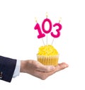 Hand handing a cupcake with a number 103 candle - Birthday on a white background Royalty Free Stock Photo