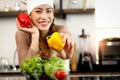 Hand of happy smiling beautiful Asian woman wearing apron and chef hat holding bell peppers at kitchen with fresh vegetables salad Royalty Free Stock Photo