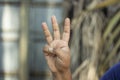 A hand has two fingers folded out of five fingers and the remaining three fingers are pointing upwards and the background is