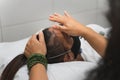 Hand of a healer applying reiki on the forehead of a lying young woman