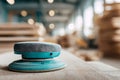 A hand-held electric sander covered in fine dust resting on a wooden surface with blurred workshop stacks and lights in the Royalty Free Stock Photo