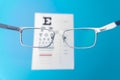 Hand-held glasses, view of the Snellen chart. Blue background Royalty Free Stock Photo