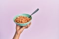 Hand of hispanic man holding bowl with italian noodles over isolated pink background Royalty Free Stock Photo