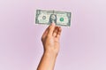 Hand of hispanic man holding one dollar banknote over isolated pink background Royalty Free Stock Photo