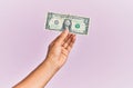 Hand of hispanic man holding one dollar banknote over isolated pink background Royalty Free Stock Photo