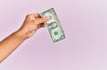 Hand of hispanic man holding one dollar banknote over isolated pink background Royalty Free Stock Photo