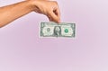 Hand of hispanic man holding one dollar banknote over isolated pink background Royalty Free Stock Photo
