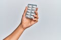 Hand of hispanic man holding pills over isolated white background Royalty Free Stock Photo