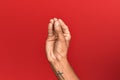 Hand of hispanic man over red isolated background doing italian gesture with fingers together, communication gesture movement Royalty Free Stock Photo