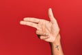 Hand of hispanic man over red isolated background gesturing fire gun weapon with fingers, aiming shoot symbol Royalty Free Stock Photo