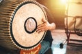 Asian male hit a two-faced drum to make music