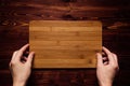 Hand hold blank bamboo sign board on brown vintage wood plank, top view.