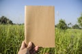 Hand hold on the brown notebook with natural light in garden outdoor at Chiang Ma,Thailand.