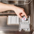 Hand hold detergent capsule on the background of the dishwasher