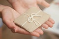 Hand hold the gift box. Present wrapped in craft paper and satin ribbon. Small parcel in a girls hands. Christmas time. Royalty Free Stock Photo