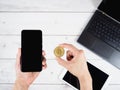 Hand hold gold bitcoin and mobilephone with laptop and tablet on wood table background Royalty Free Stock Photo