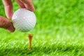 Hand hold golf ball put on tee brown wood with green grass background. Royalty Free Stock Photo