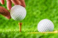 Hand hold golf ball put on tee brown wood with green grass background. Royalty Free Stock Photo