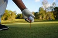 Hand hold golf ball with tee on course, golf course background Royalty Free Stock Photo