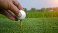 Hand hold golf ball with tee on course, golf course background Royalty Free Stock Photo