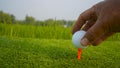 Hand hold golf ball with tee on course, golf course background Royalty Free Stock Photo