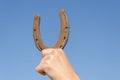 Hand hold horseshoe symbol of luck on blue sky