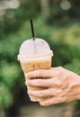 Hand hold iced latte coffee in a glass. cold summer drink background