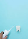 Hand hold irrigator near tooth model on blue background, professional clean teeth, teeth will good healthy. Dentist stomatology Royalty Free Stock Photo