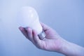 Hand hold LED light bulb on blue background defocus. Royalty Free Stock Photo