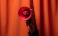 Hand hold megaphone on orange curtains