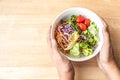 hand hold mixed Salad bowl on wooden table Royalty Free Stock Photo