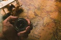 Hand hold old compass discovery and wooden plane on vintage paper antique world map Royalty Free Stock Photo