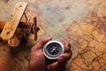 Hand hold old compass discovery and wooden plane on vintage paper antique world map Royalty Free Stock Photo