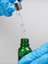 Hand hold pipette with medicine oil in a bottle on gray background