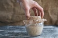 Hand hold or puts glass jar with rye sourdough on table, yeast-free leaven starter for healthy organic rustic bread Royalty Free Stock Photo