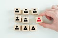 Hand hold red people icon on cube. Recruiter complete team by one leader person.