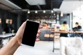 Hand hold smart phone,mobile over blurred image of coffee shop