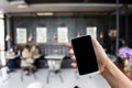 Hand hold smart phone, mobile over blurred image of coffee shop