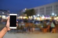 hand hold and touch screen smart phone, on blurred photo of people shopping at night market. Royalty Free Stock Photo