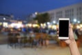 hand hold and touch screen smart phone, on blurred photo of people shopping at night market. Royalty Free Stock Photo