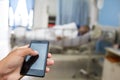 Hand hold and touch screen smart phone, over blurred hospital background. Royalty Free Stock Photo