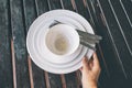 Hand hold used white bowl and plate with fork and spoon on wooden table Royalty Free Stock Photo