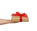 Hand hold a wrapped gift in brown craft paper with tied silk red bows, subject is isolated on a white background Royalty Free Stock Photo
