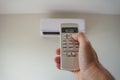 Hand holding the air conditioner remote control and thumb is pressing a button on the remote, Royalty Free Stock Photo