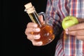 hand holding apple vinegar in glass bottle with fresh green apple