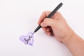 Hand holding a artist black ink pen hand sketched Purple Heart on white background