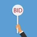 Hand holding auction paddle. BID. Royalty Free Stock Photo