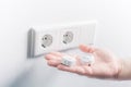 Hand Holding Baby Safety Plugs In Front Of A Wall Socket - Child Safety Concept Royalty Free Stock Photo