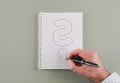 Hand holding ballpoint pen drawing question mark on spiral notepad Royalty Free Stock Photo